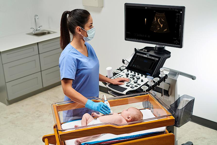 Η εικόνα δείχνει έναν ιατρό που εκτελεί υπερηχογραφική εξέταση ήπατος σε ένα μωρό.