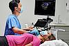 Na zdjęciu widać lekarza przeprowadzającego badanie ultrasonograficzne tarczycy  u pacjenta.