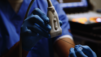 Eine Ärztin scannt eine Injektionsnadel mit einer Ultraschallsonde