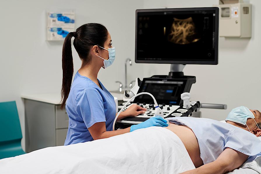 Imaginea prezintă un medic care efectuează o ecografie abdominală unui pacient.