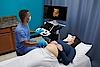 Imaginea prezintă un medic care efectuează o ecografie unei paciente însărcinate.