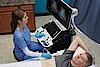 Obrázek znázorňuje lékaře provádějícího břišní ultrazvukové vyšetření u pacienta.
