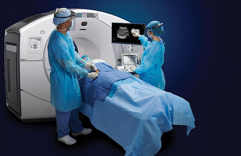 Obrázek znázorňuje dva lékaře provádějící intervenční ultrazvukové vyšetření u pacienta.