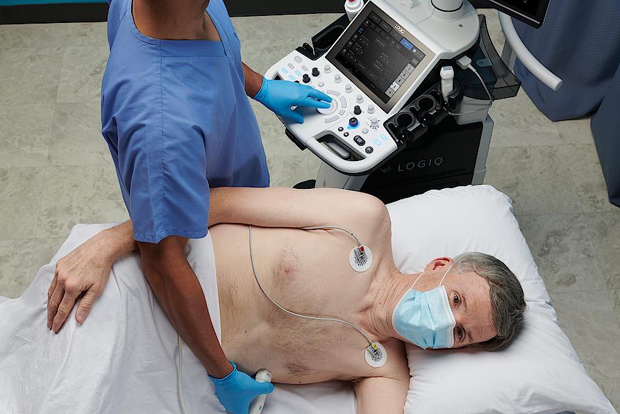 Das Bild zeigt einen Arzt, der bei einem Patienten eine Ultraschalluntersuchung des Herzens durchführt.