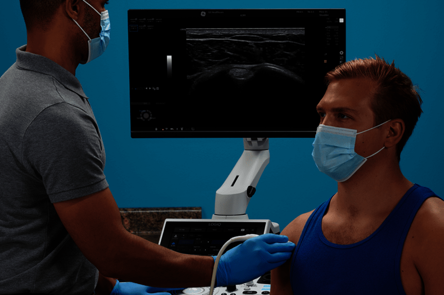 Η εικόνα δείχνει έναν ιατρό που εκτελεί μυοσκελετική υπερηχογραφική εξέταση στον ώμο ενός ασθενούς.