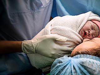 A doctor is handing a mother her newborn baby