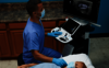 Η εικόνα δείχνει έναν ιατρό που εκτελεί υπερηχογραφική εξέταση θυροειδούς σε έναν ασθενή.