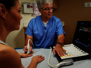 Eine Ärztin führt eine Ultraschalluntersuchung am Finger einer Patientin durch