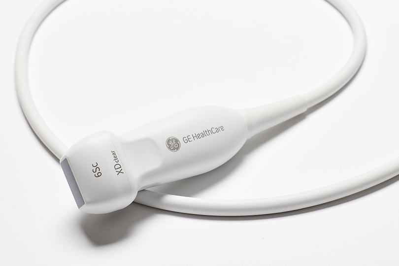 Nahaufnahme einer weißen GE Healthcare 6Sc XDclear-Ultraschallsonde und eines Kabels, die auf einer weißen Oberfläche liegen