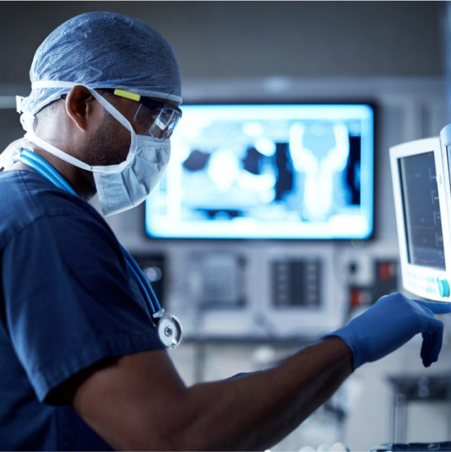 A doctor in scrubs is standing in an operation room, working on his ultrasound system